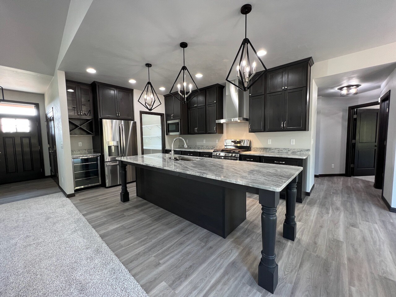 Black kitchen island with grey and white marble pattern countertop.