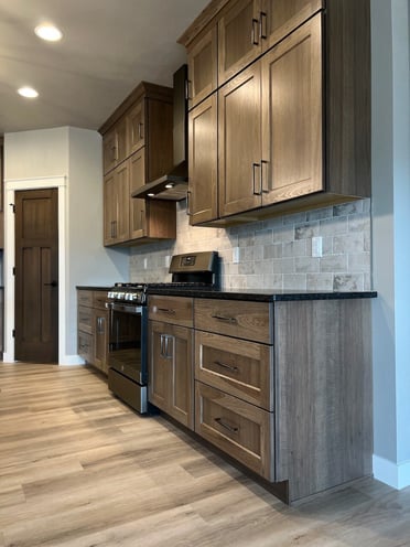 Black hood range with dark wood cabinets.