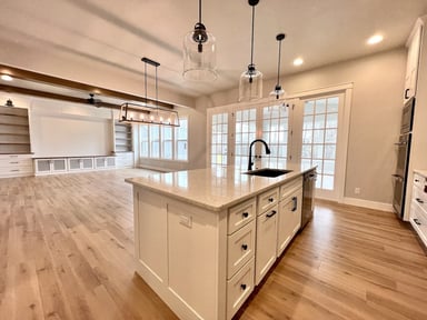 White kitchen island, with lots or drawers, a sink, and white countertop.